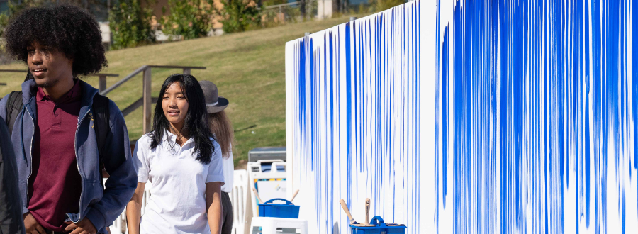 6 of 8, College ages students walking by large white canvases covered in blue lines